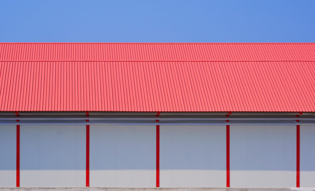 White sandwich panel wall and red metal gable roof of 2 industrial cold storage warehouse buildings